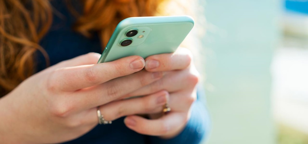 Manos de mujer pelirroja sujetando un móvil