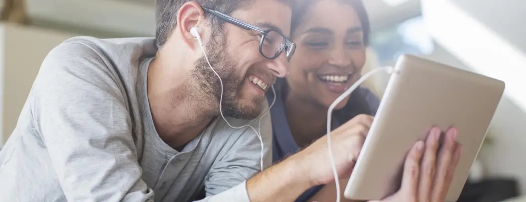 Pareja con auriculares usando una tablet