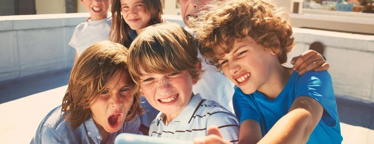 Niños en la calle mirando la pantalla de un dispositivo móvil